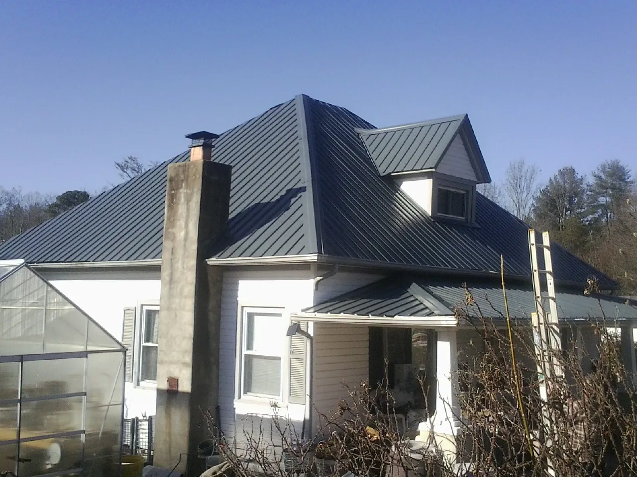 Dark blue standing seam metal roof on a white farmhouse with dormer — Slate & Tile Roof Repair by Roofing Brothers in San Bernardino