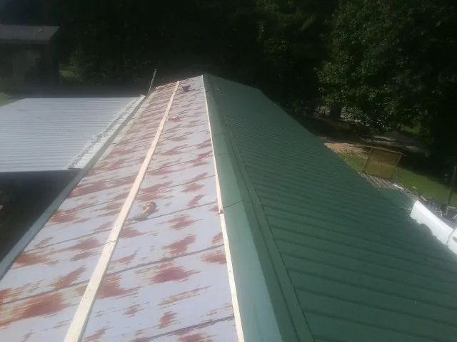 Old rusted panels beside newly installed green metal roofing — Wind Damage Roof Repair by Roofing Brothers in San Bernardino
