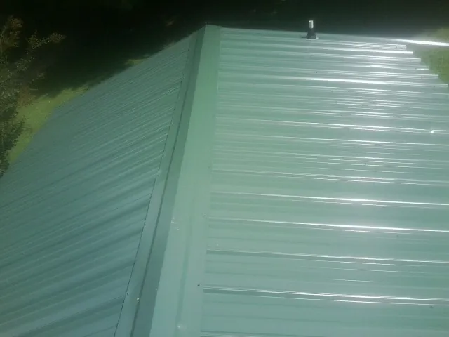 New green metal panels meeting at the ridge of a roof — Flat Roof Repair work by our crew in San Bernardino
