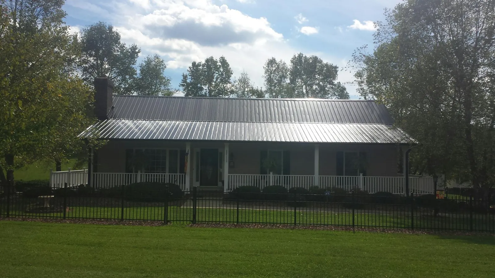 Gray metal roof on a brick ranch with a full width front porch — Gutter Guard Installation work by our crew in San Bernardino