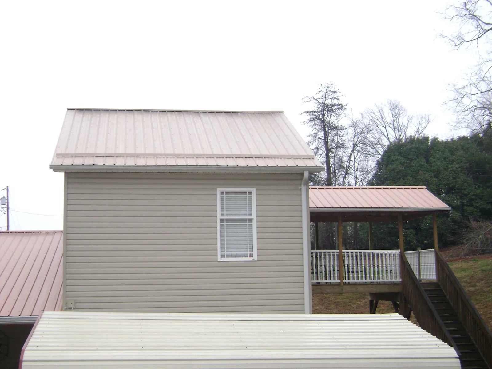 Tan metal roofs on a two story addition and attached porch, from a Roof Replacement job in San Bernardino